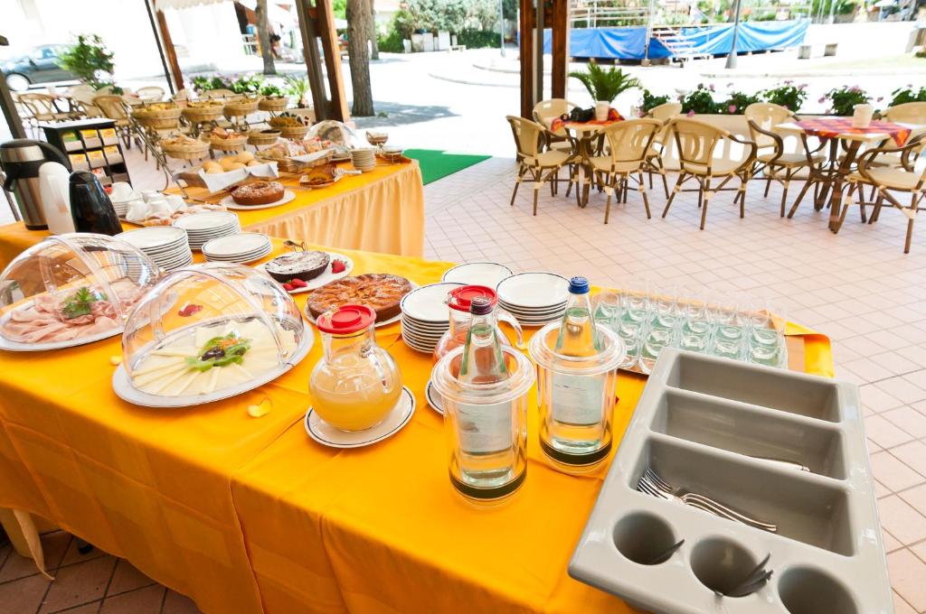 une table jaune avec des assiettes de nourriture dessus dans l'établissement Hotel Milan, à Rosolina Mare