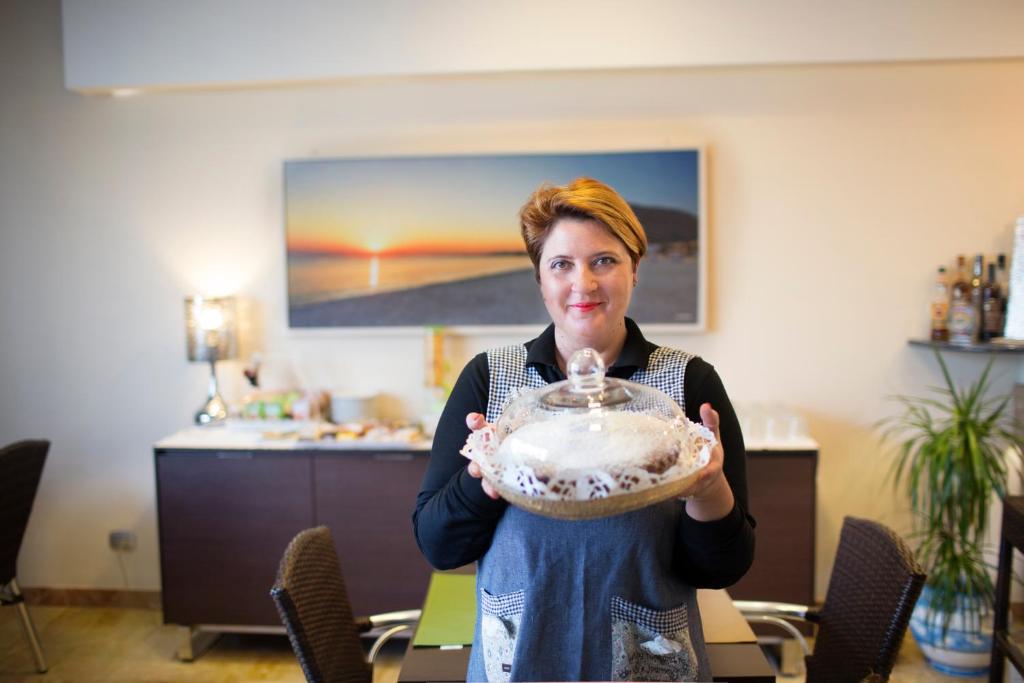 une femme tient un bol dans une pièce dans l'établissement Hotel Piccolo Mondo, à San Vito Lo Capo