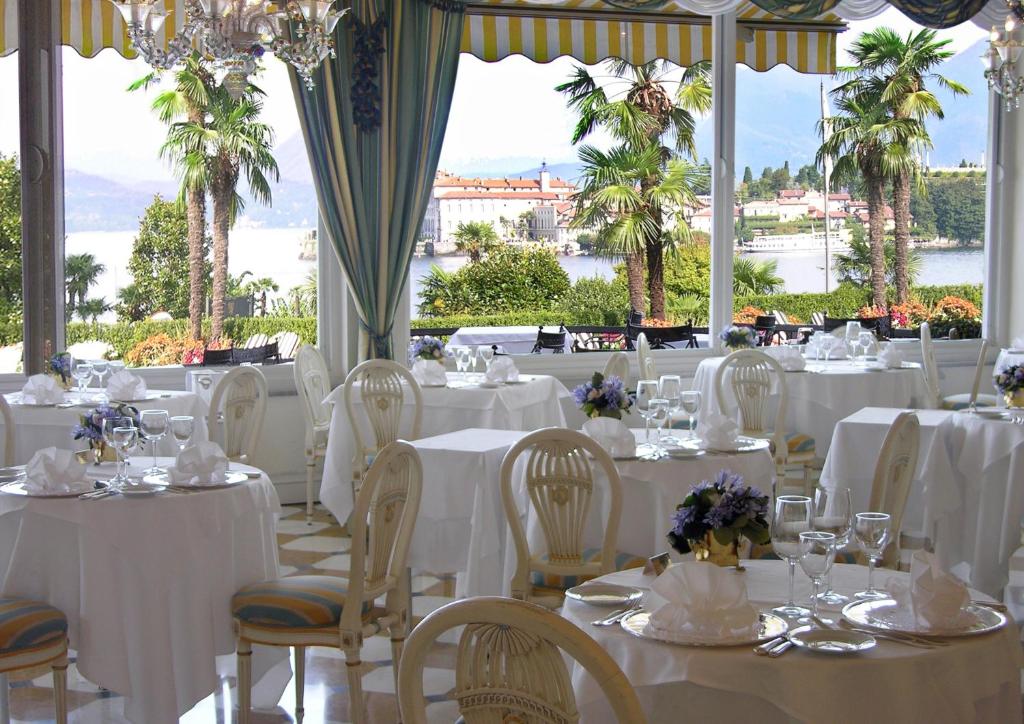- un restaurant avec des tables et des chaises blanches offrant une vue dans l'établissement Villa e Palazzo Aminta - A Leading Hotel of The World, à Stresa