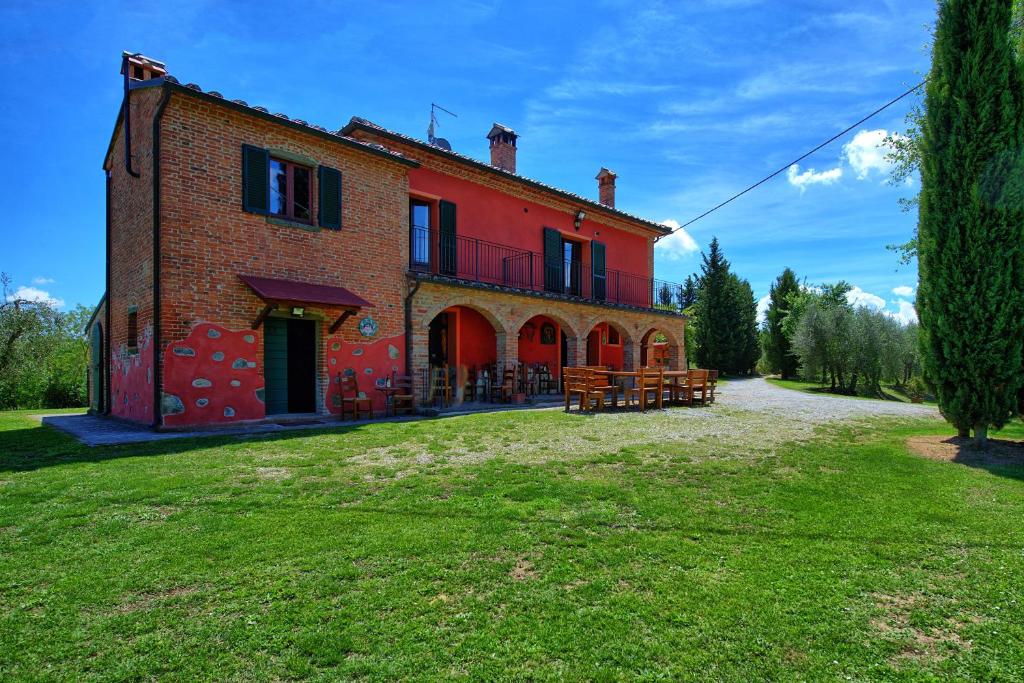 un bâtiment en briques rouges avec bancs devant lui dans l'établissement Villa Mario by PosarelliVillas, à Lucignano