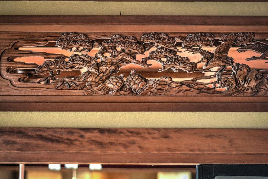 une photo en bois des animaux sur un mur dans l'établissement K's House Ito Onsen - Historical Ryokan Hostel, à Itō