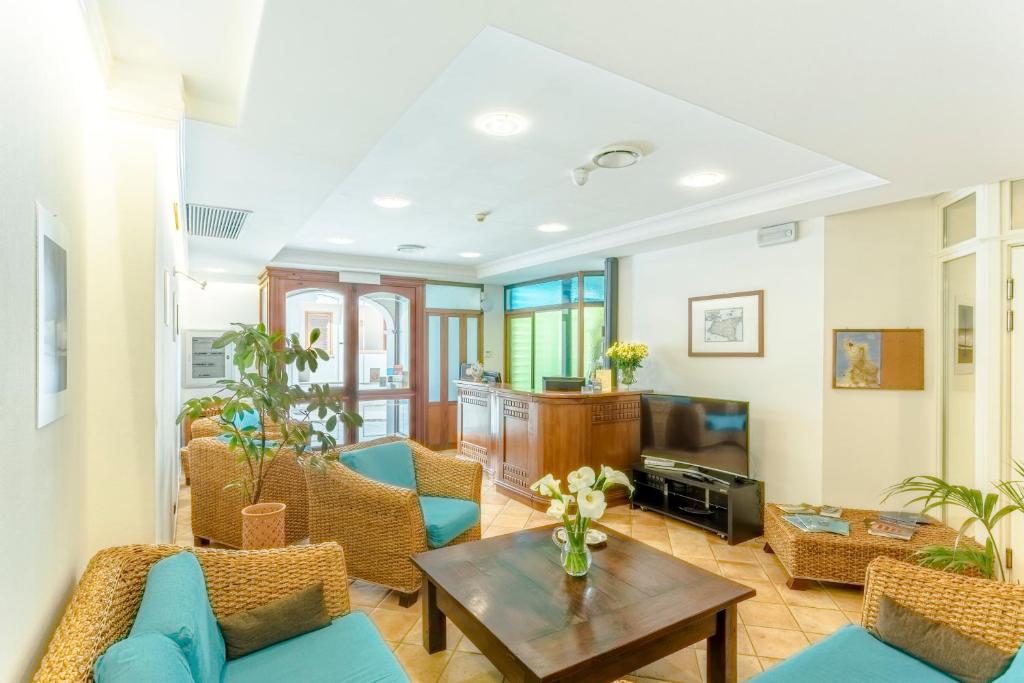un salon avec des chaises bleues et une table dans l'établissement Hotel Trinacria, à San Vito Lo Capo