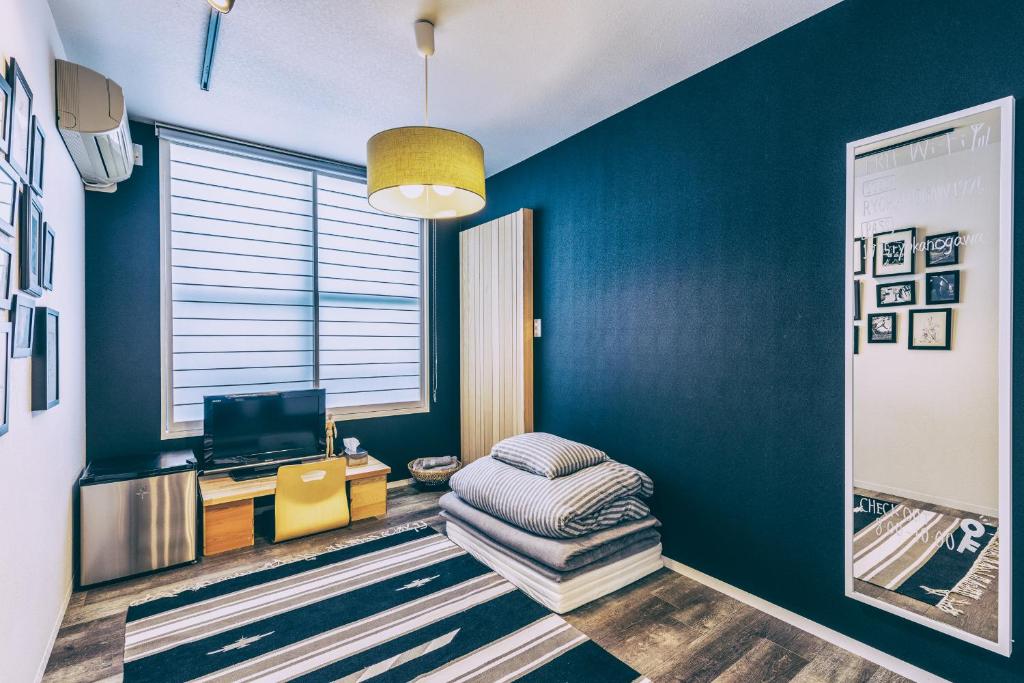 Cette chambre est dotée d'un mur bleu, d'une chaise et d'une télévision. dans l'établissement Ogawa Ryokan, à Shimoda