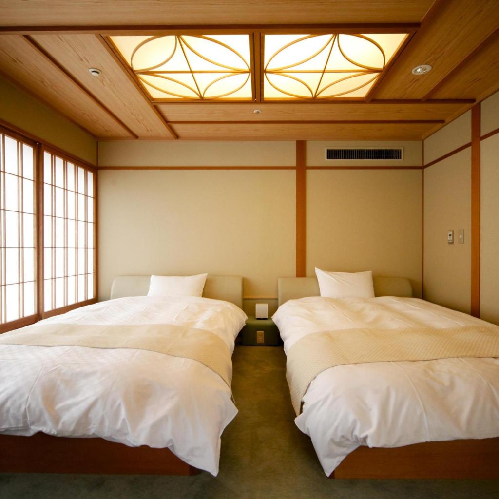deux lits dans une chambre avec deux fenêtres dans l'établissement Kotohira Onsen Kotosankaku, à Kotohira 32 autres photos