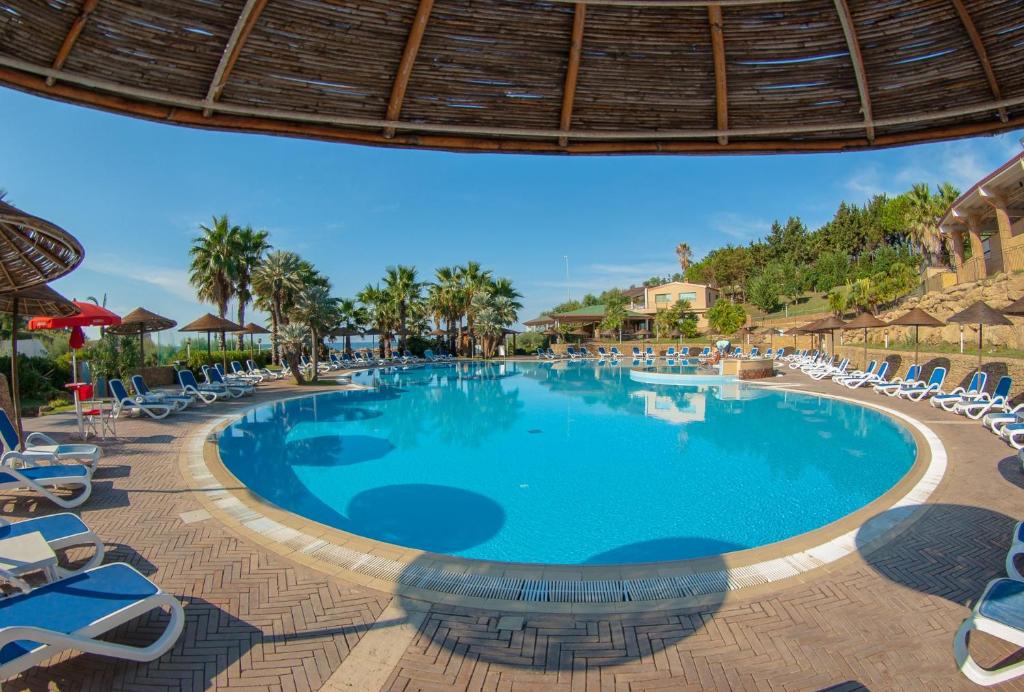 une piscine dans un complexe hôtelier avec des chaises longues dans l'établissement TH Le Castella - Baia degli Dei Village, à Le Castella