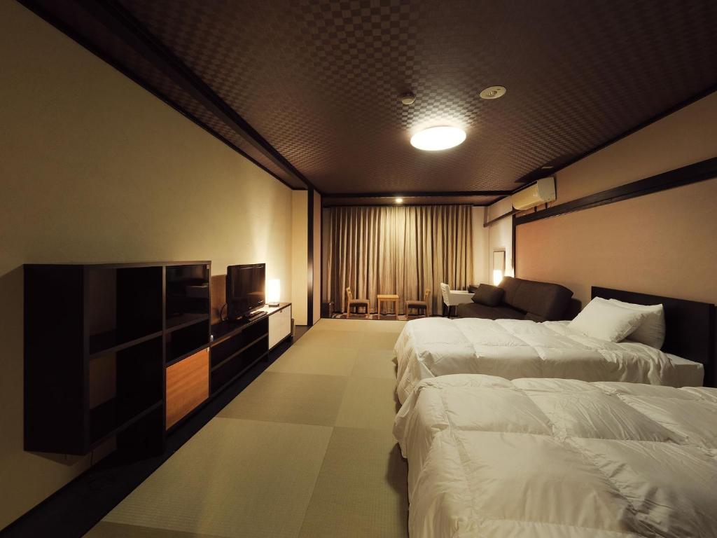 une chambre d'hôtel avec deux lits et une télévision dans l'établissement Shiobara Onsen Tokiwa Hotel, à Nasushiobara