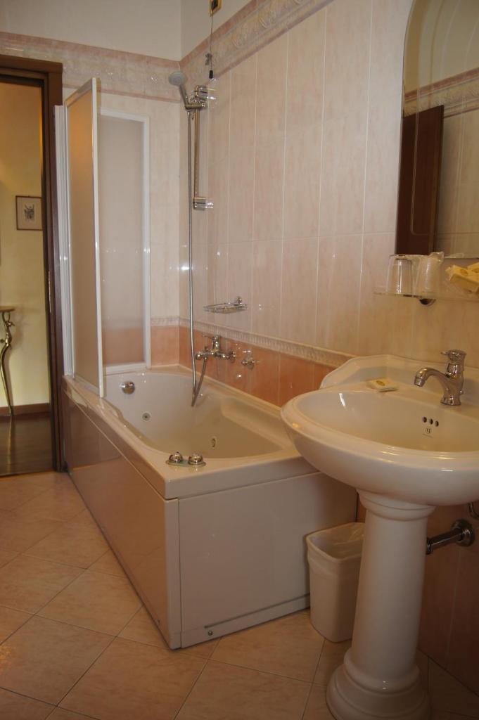 une salle de bain avec un lavabo et une baignoire et un lavabo dans l'établissement Hotel Lugana Parco Al Lago, à Sirmione