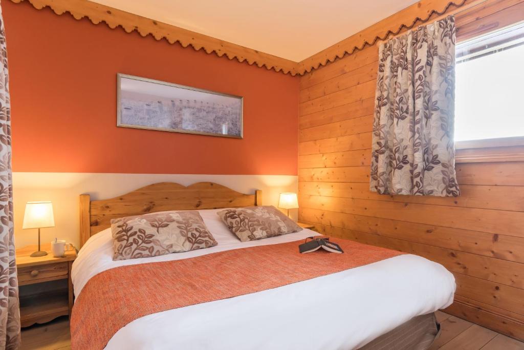 - une chambre avec un lit aux murs orange et une fenêtre dans l'établissement Résidence Pierre & Vacances Premium Les Hauts Bois, à Aime La Plagne