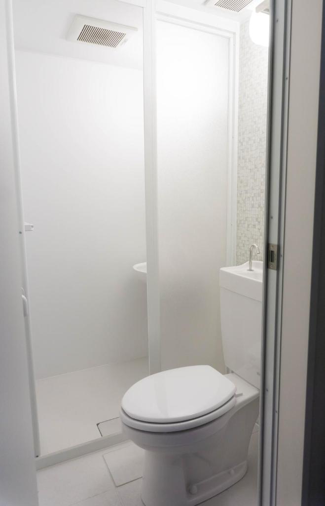 une salle de bain blanche avec toilettes et douche dans l'établissement Ryokan Hinomoto Kyoto Kawaramachi, à Kyoto