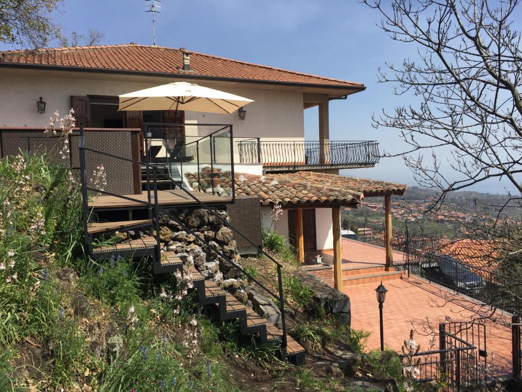 une maison avec des escaliers menant à elle avec un parasol dans l'établissement Villa Maria, à Zafferana Etnea
