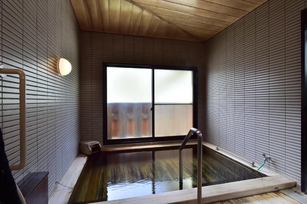 une baignoire dans une pièce avec une fenêtre dans l'établissement Ryokan Hakura, à Yamanouchi