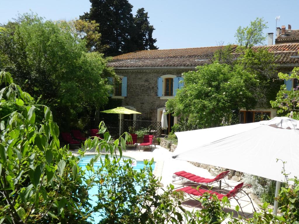 une maison avec une piscine, des chaises et un parasol dans l'établissement Gîte Eloi Merle, à Olonzac