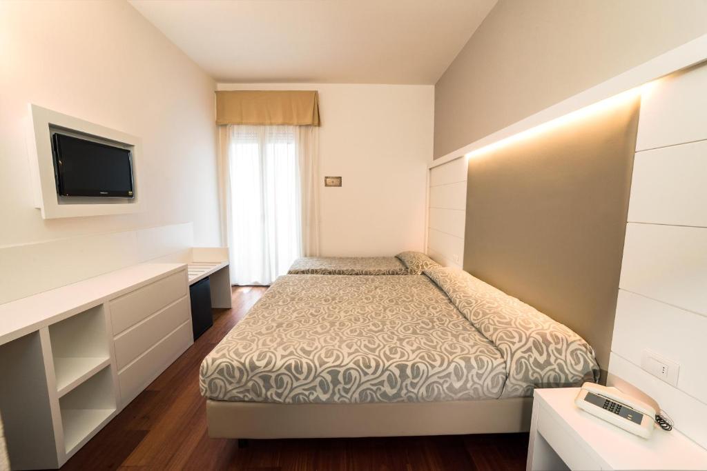 une petite chambre avec un lit et une télévision dans l'établissement Hotel Alexander, à Cattolica