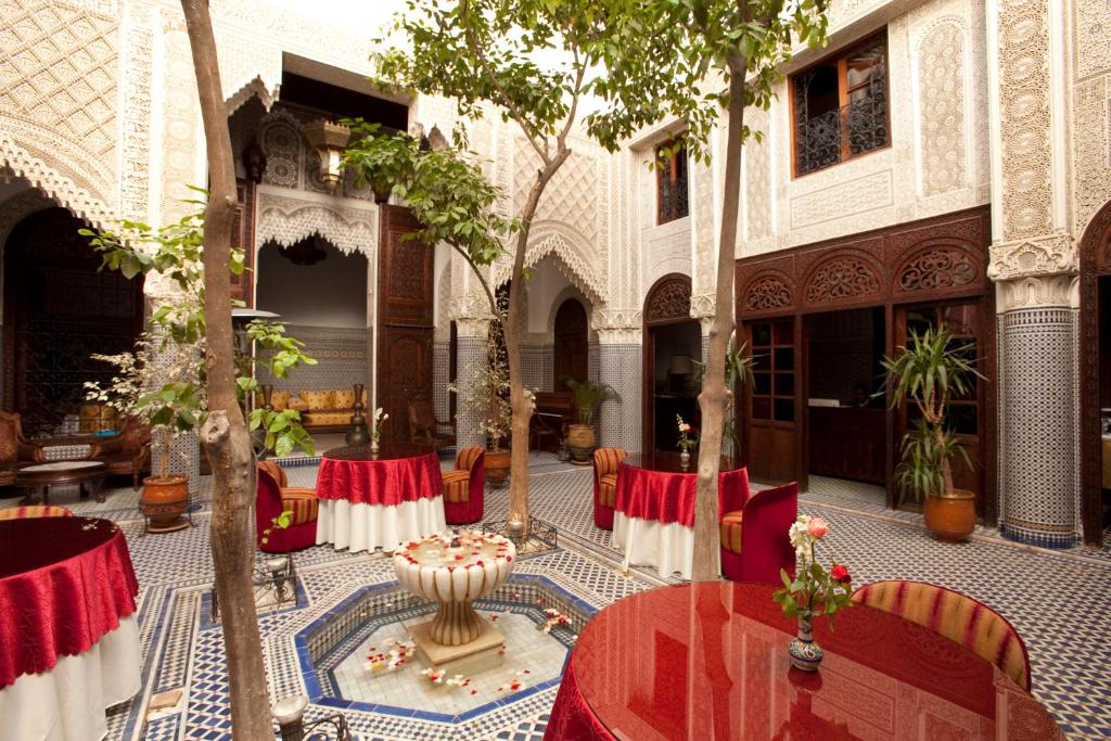 une cour avec des tables et des chaises dans un bâtiment dans l'établissement Riad Alya, à Fès