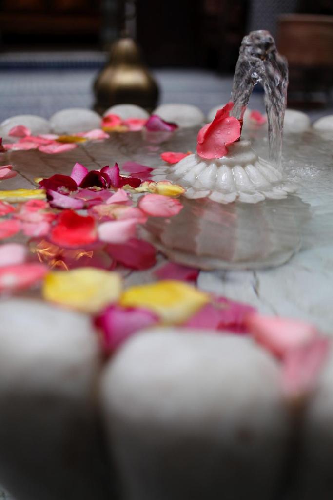 une fontaine avec des fleurs sur une table dans l'établissement Riad Alya, à Fès