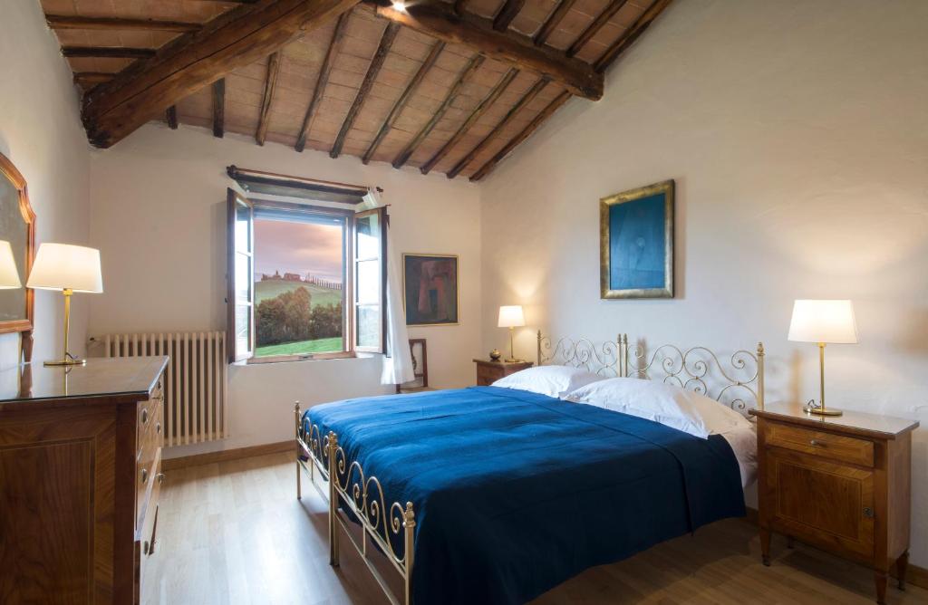 une chambre avec un lit avec des draps bleus et une fenêtre dans l'établissement Villa Le Caggia, à Sovicille