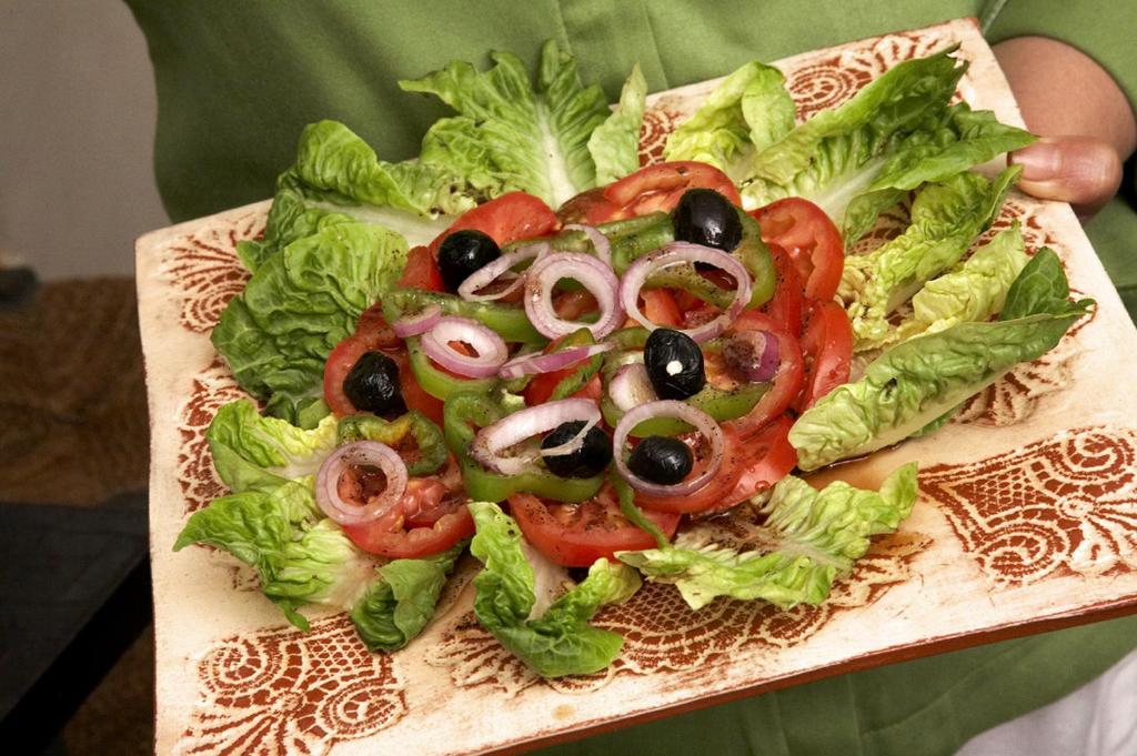 une salade avec des olives et des tomates sur un plateau de découpe dans l'établissement Riad Davia, à Marrakech