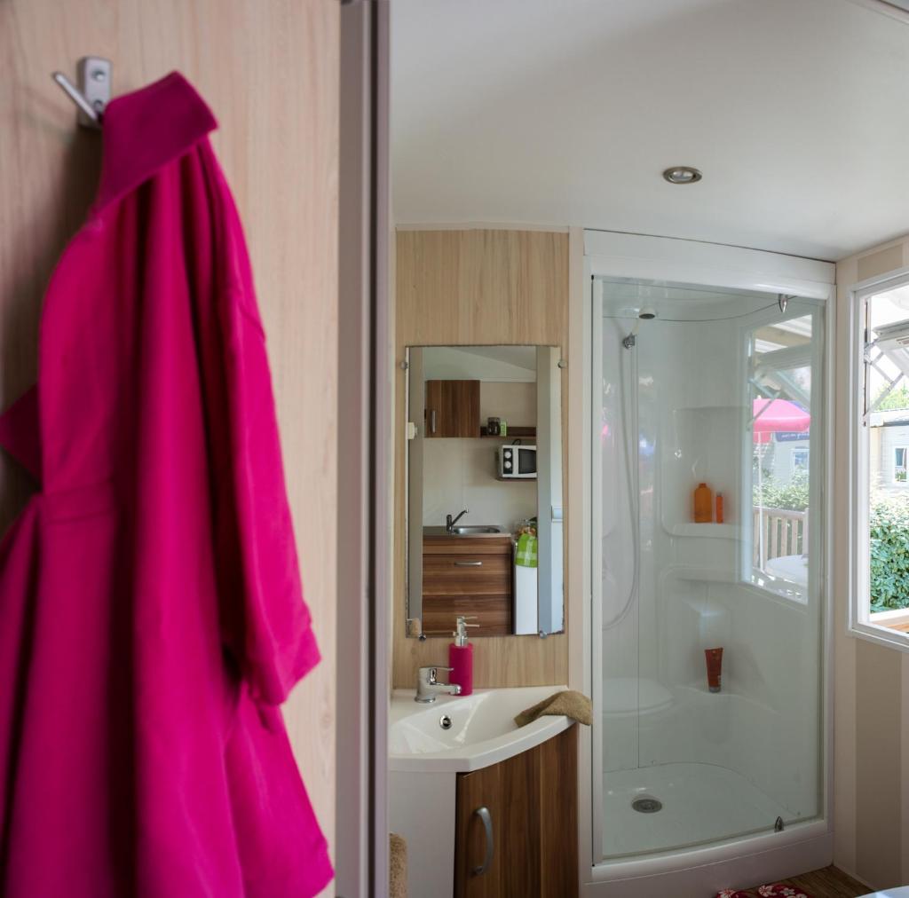- une salle de bains pourvue d'une robe rose accrochée au mur dans l'établissement Camping Officiel Siblu Les Rives de Condrieu, à Condrieu