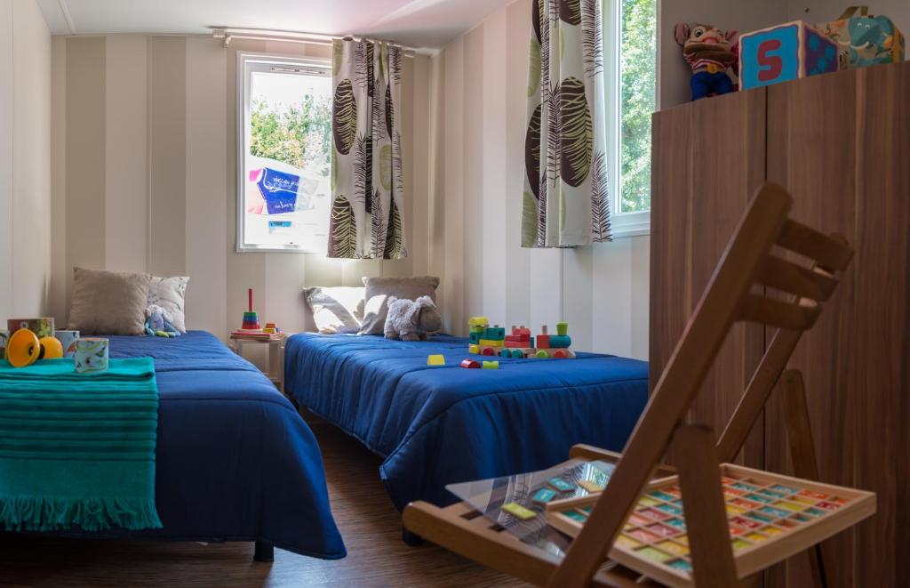- 2 lits dans une chambre avec des draps bleus dans l'établissement Camping Officiel Siblu Les Rives de Condrieu, à Condrieu