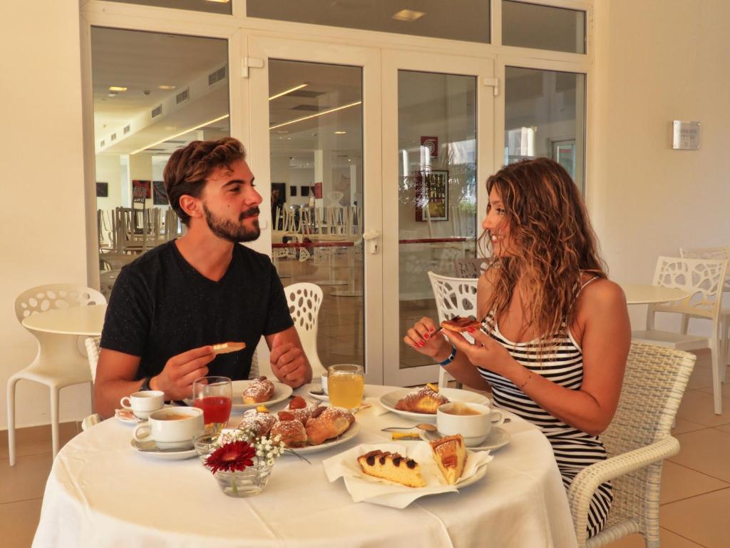 un homme et une femme assis à une table mangeant de la nourriture dans l'établissement Futura Club Spiagge Bianche, à Fontane Bianche