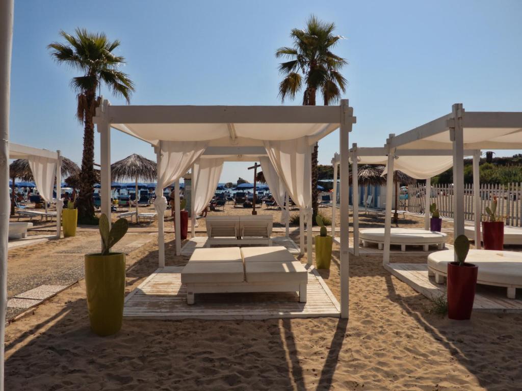 - un kiosque sur la plage avec des chaises et des palmiers dans l'établissement Futura Club Spiagge Bianche, à Fontane Bianche