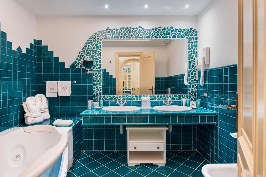 La salle de bains bleue est pourvue de 2 lavabos et d'un miroir. dans l'établissement Hotel Hermitage, à Portoferraio