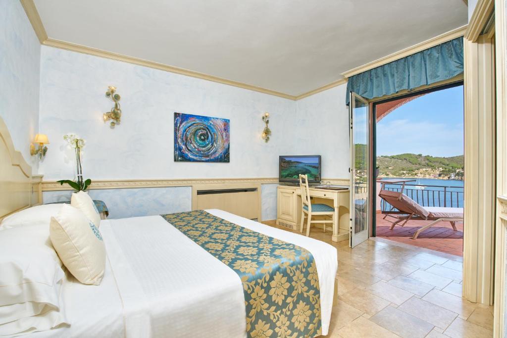 une chambre avec un lit et un bureau et un balcon dans l'établissement Hotel Hermitage, à Portoferraio