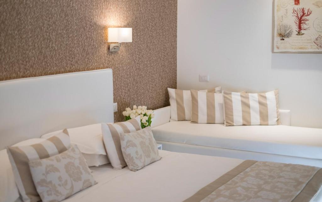 Cette chambre blanche comprend 2 lits et un vase de fleurs. dans l'établissement Hotel Mon Cheri, à Riccione