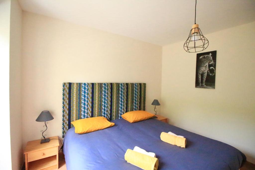 - une chambre avec un grand lit bleu et des oreillers jaunes dans l'établissement Gite Lou Peyrol, à Urval