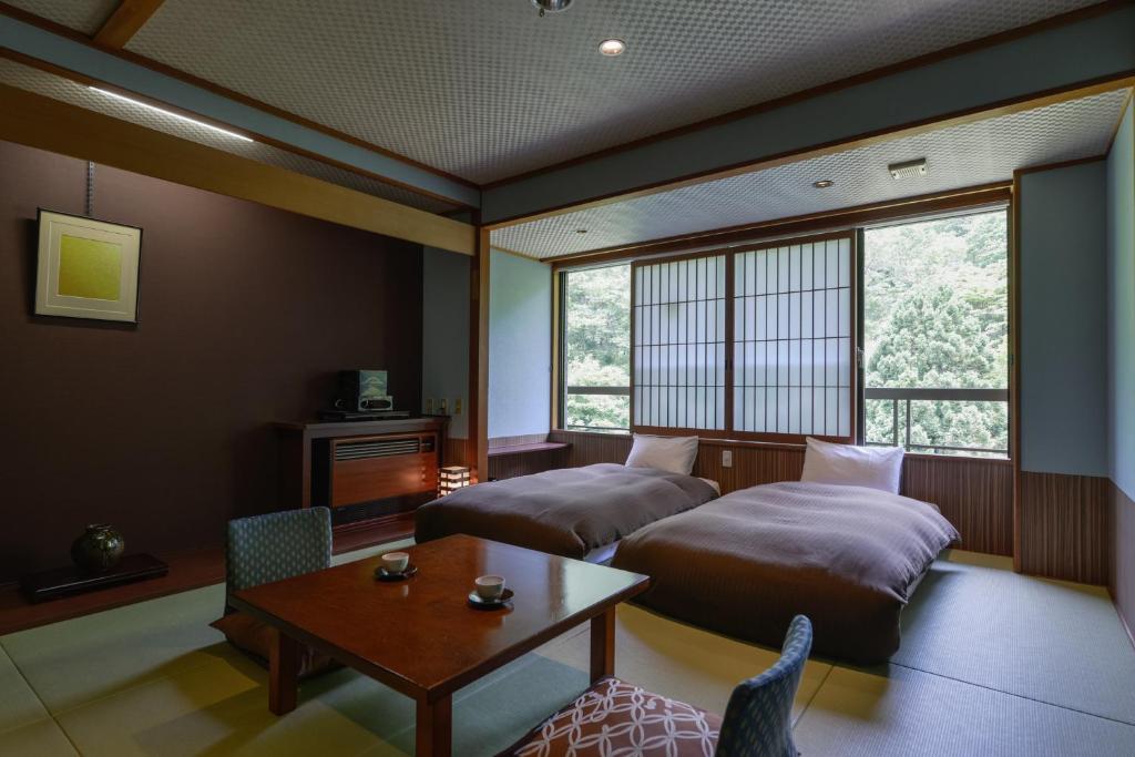Cette chambre comprend 2 lits, une table et une table. dans l'établissement Takamiya Bettei Kuon, à Tsuruoka
