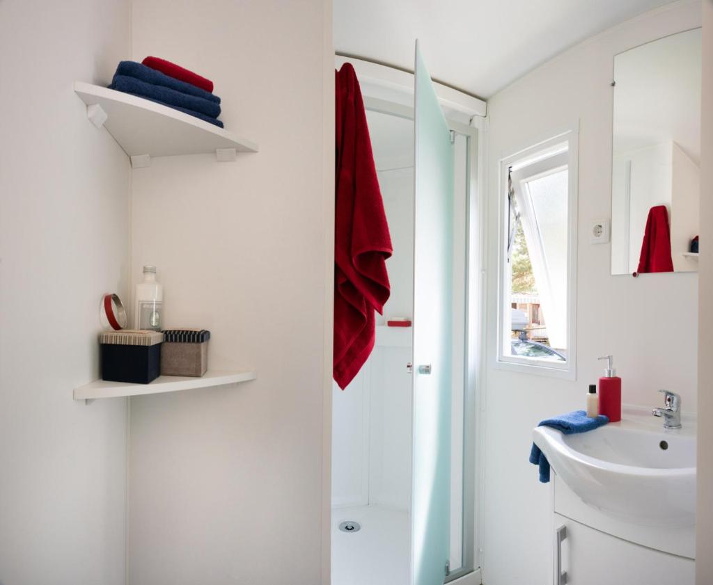 une salle de bain blanche avec une douche et un lavabo dans l'établissement Camping Officiel Siblu La Carabasse, à Vias