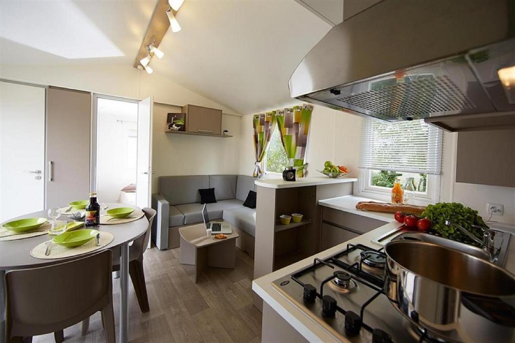 Il comprend une cuisine et un salon avec une table et une cuisinière. dans l'établissement Camping Officiel Siblu le Montourey, à Fréjus