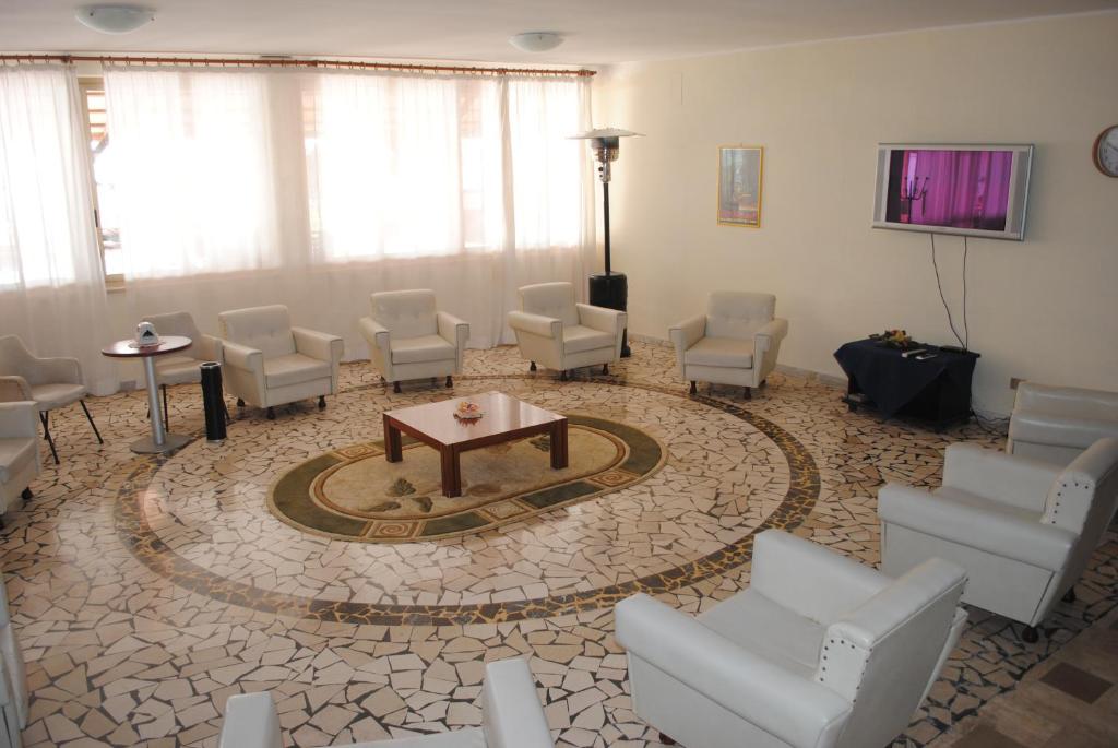 - une salle d'attente avec des chaises blanches et une table dans l'établissement Hotel South Paradise, à Palmi