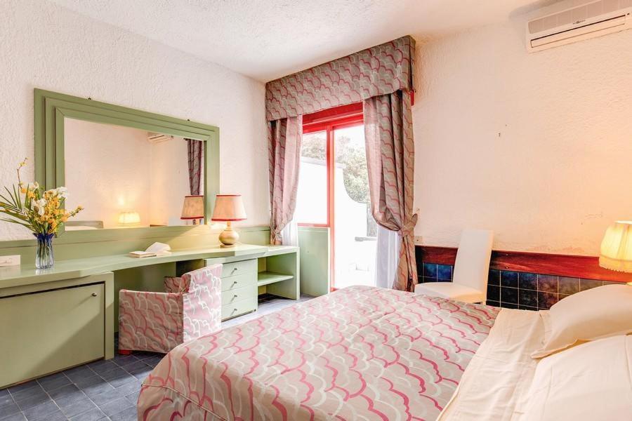 une chambre avec un lit, un bureau et un miroir dans l'établissement Marina Club Hotel, à Baia Domizia 76 autres photos