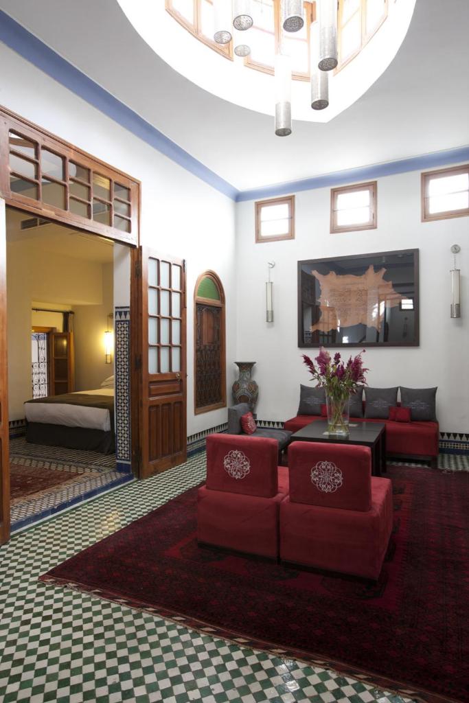 - un salon avec un mobilier rouge et un lit dans l'établissement Palais Amani, à Fès