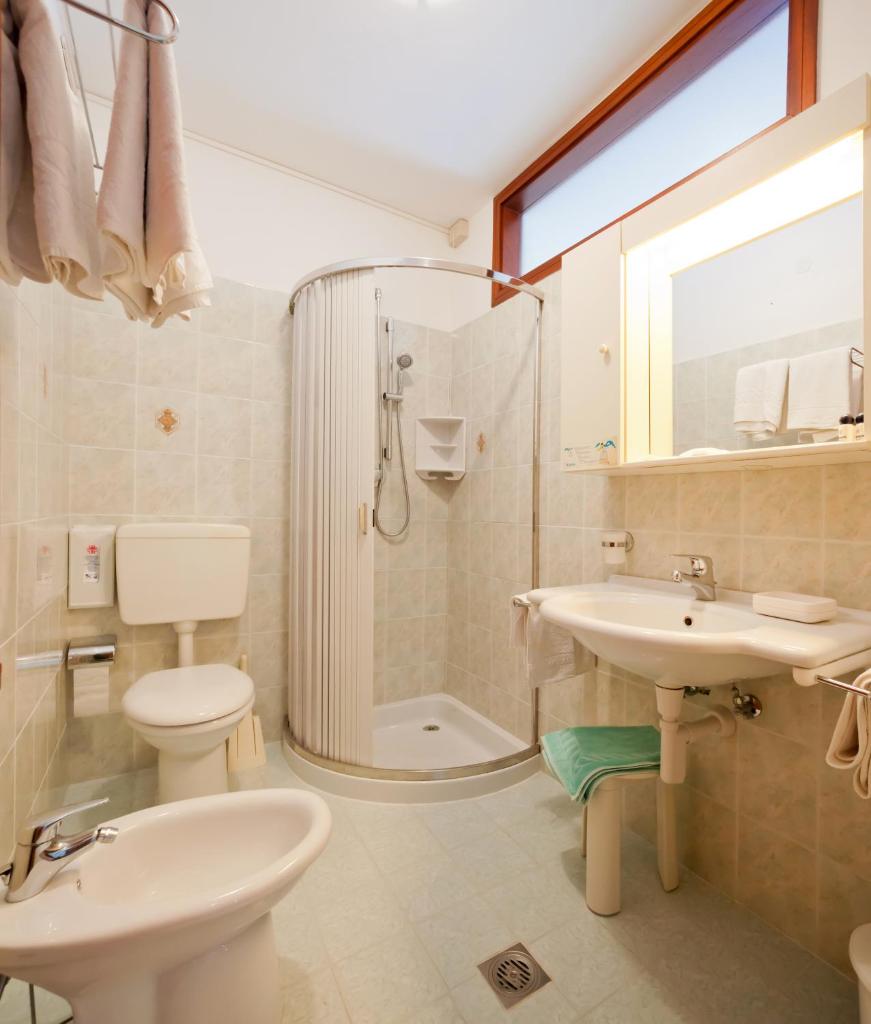 une salle de bain avec toilettes, lavabo et douche dans l'établissement Hotel Universal, à Caorle