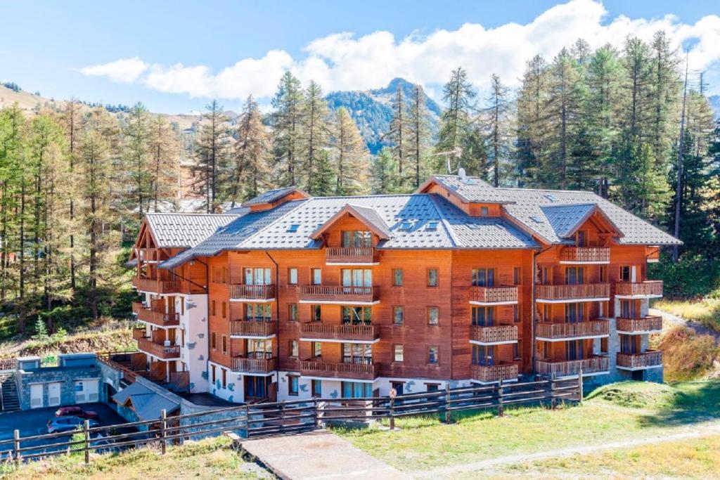 une image d'un grand immeuble dans les montagnes dans l'établissement Residence Albane - maeva Home, à Vars