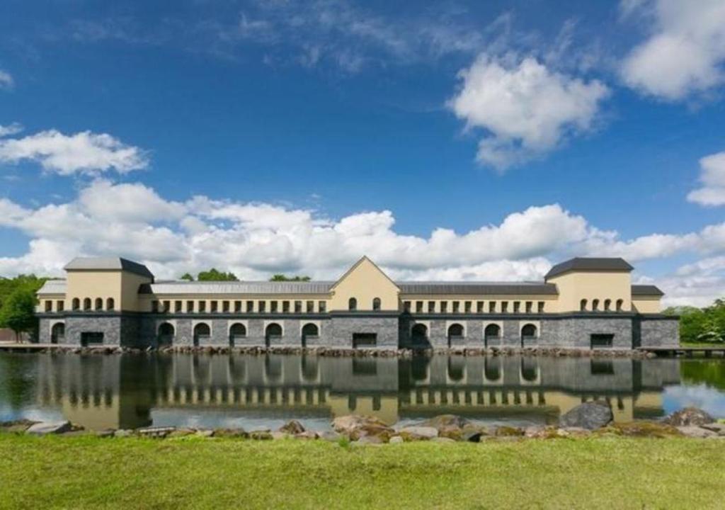 un grand bâtiment avec un lac en face dans l'établissement Higashiyama Park Hotel Shinfugetsu, à Aizuwakamatsu