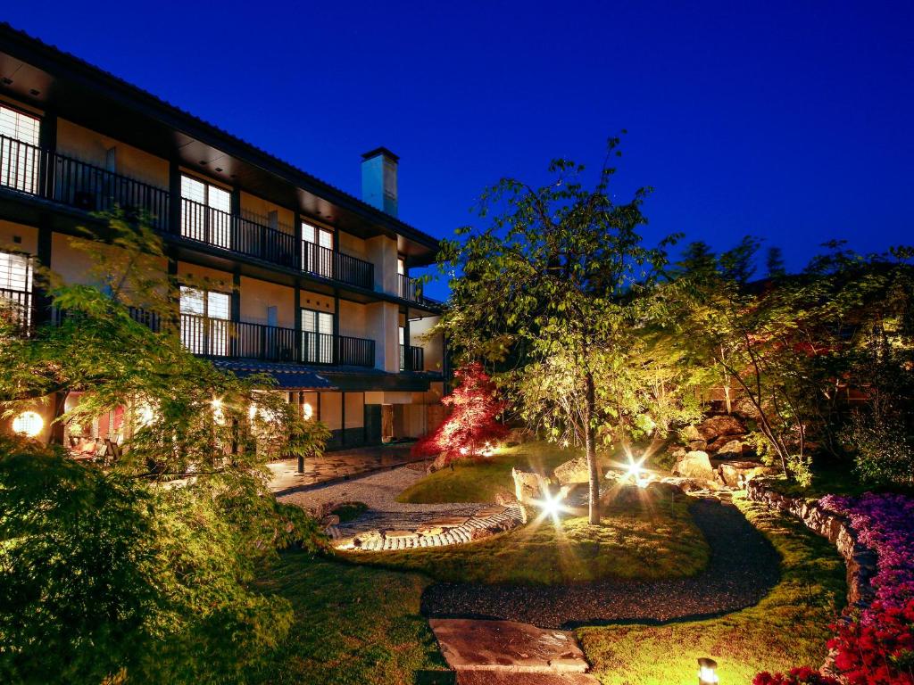 un bâtiment avec des lumières dans un jardin la nuit dans l'établissement Ryokan KANADE, à Kyoto