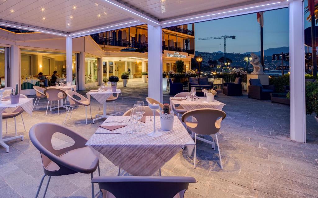 un restaurant avec des tables et des chaises blanches sur la terrasse dans l'établissement Best Western Regina Elena, à Santa Margherita Ligure