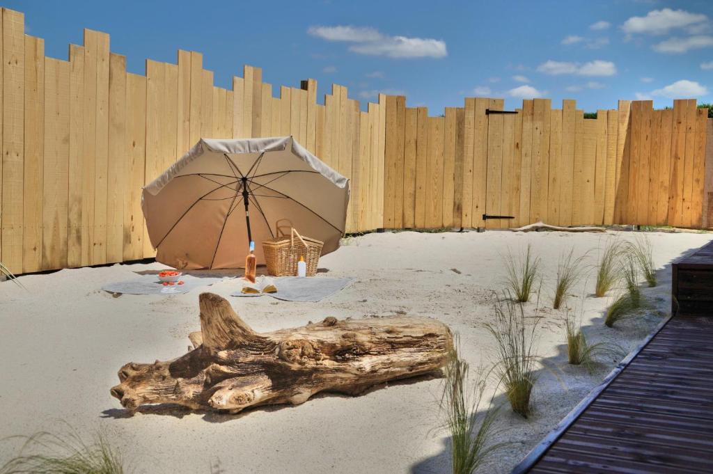 une clôture en bois et un parasol dans le sable dans l'établissement Villa l'estuaire Gîte, à Braud-et-Saint-Louis