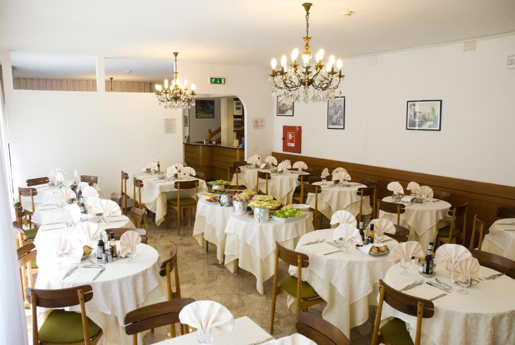 une salle à manger remplie de tables avec des nappes blanches dans l'établissement Hotel Carezza, à Cervia
