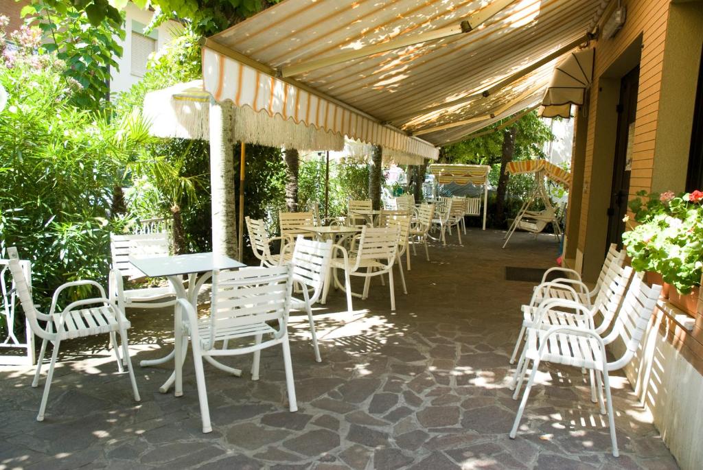 - une rangée de chaises et de tables blanches sur une terrasse dans l'établissement Hotel Carezza, à Cervia