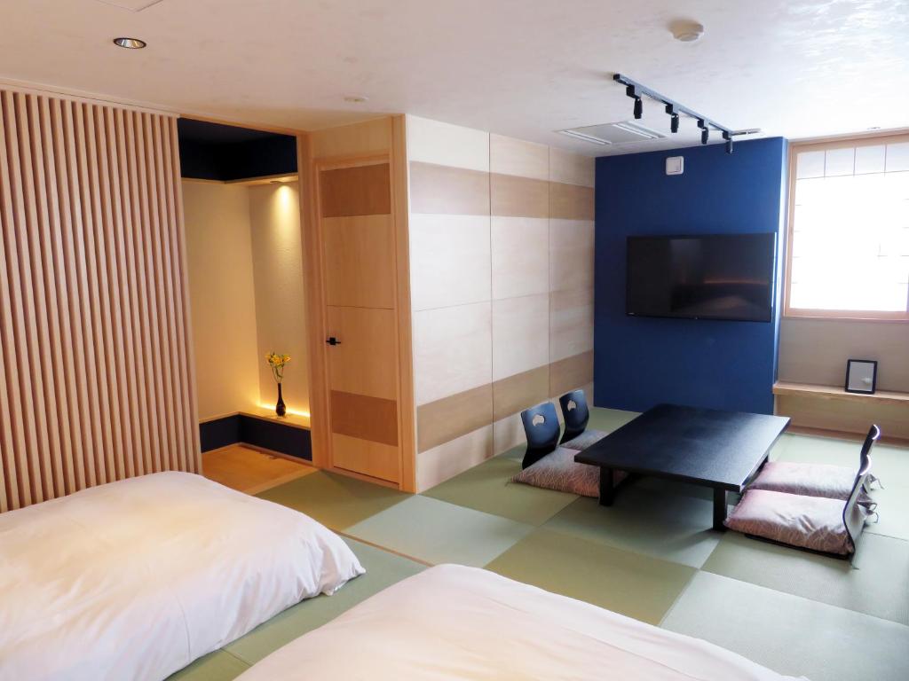 une chambre avec un lit, une table et une télévision dans l'établissement Kashoutei Hanaya, à Noboribetsu