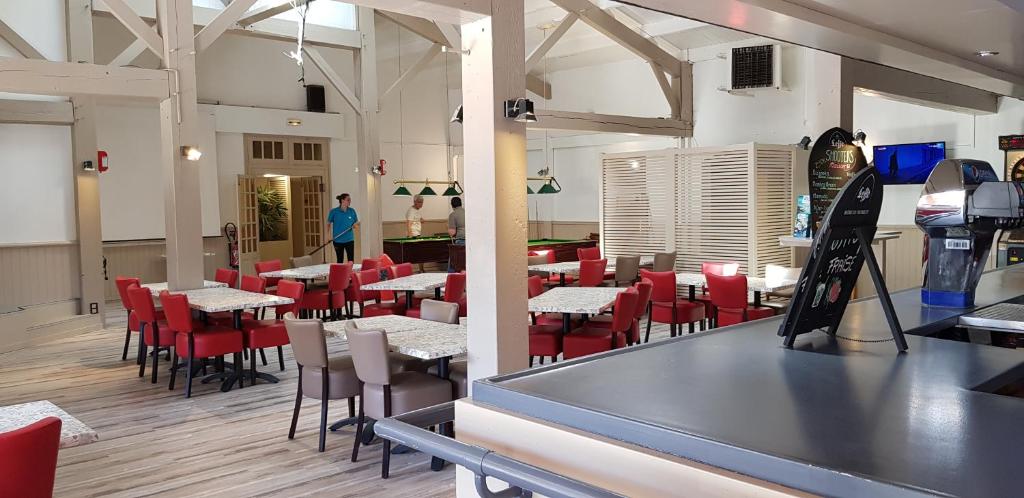 une salle à manger avec des tables et des chaises rouges et un homme dans l'établissement My mobil homes, à Saint-Jean-de-Monts