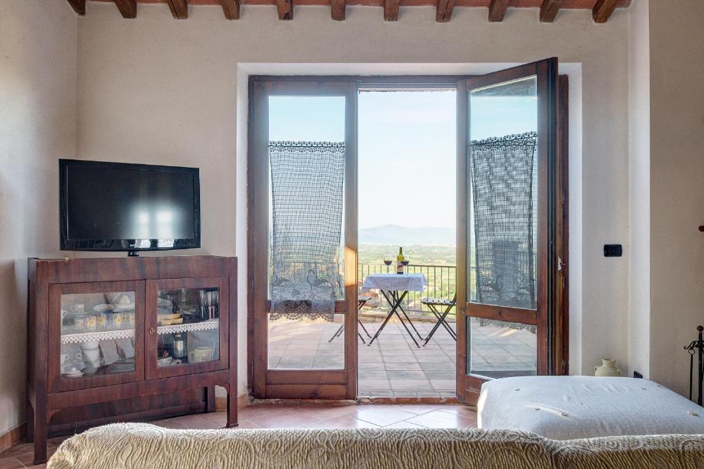 - un salon avec une télévision et une porte coulissante en verre dans l'établissement SacroFanum Villa, à Sinalunga