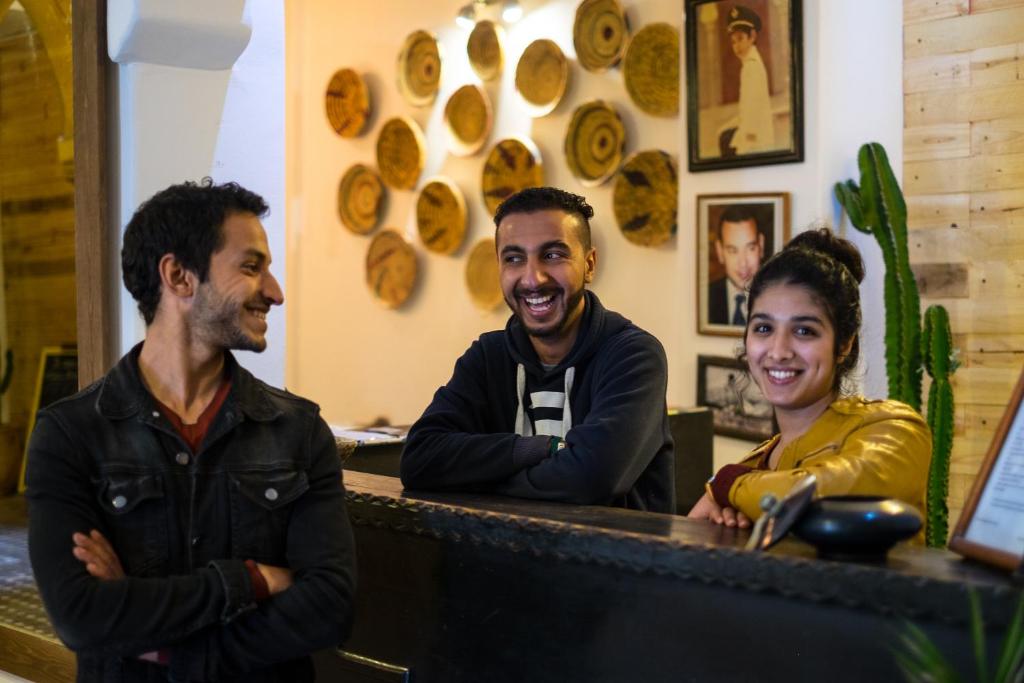 Un groupe de trois personnes assises à un comptoir dans l'établissement Riad Inna & Watersports Center, à Essaouira