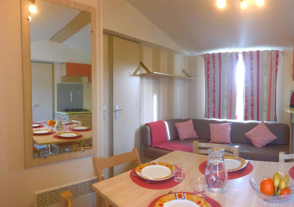 un salon avec une table et un canapé dans l'établissement Mobilhome Climatisé 3CH 6P dans Parc des 7 Fonts, à Agde