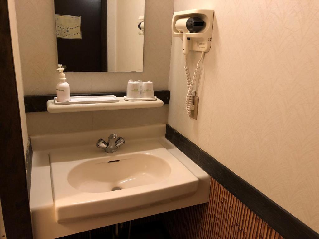 une salle de bain avec un lavabo et un miroir dans l'établissement Onyado Hisui, à Takayama