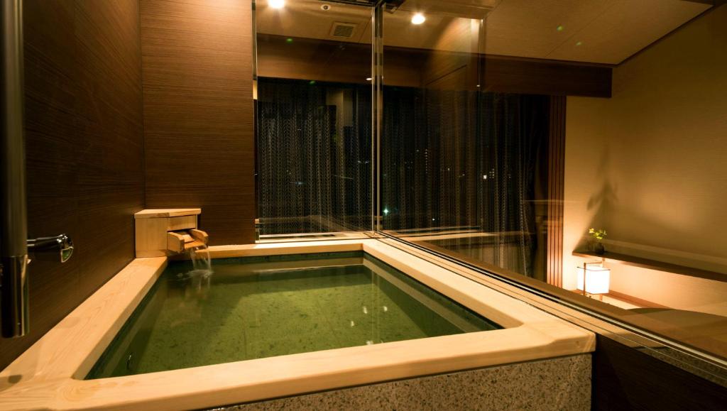 une baignoire dans une salle de bain avec une grande fenêtre dans l'établissement Laforet Ito Onsen Yunoniwa, à Itō